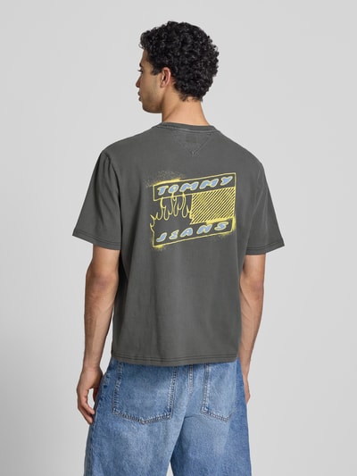 Männermodel trägt Regular Fit T-Shirt aus reiner Baumwolle Modell '90s' von Tommy Jeans, Unifarbe, Label Print, Rückenansicht Ganzkörperansicht.