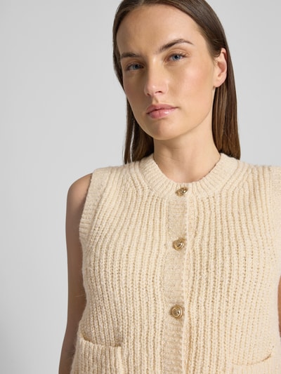 Frauenmodel trägt Strickweste Melange Effekt mit Schmuckknopf von Christian Berg Woman aus Baumwoll-Mix in Beige, Nahaufnahme Oberkörper.