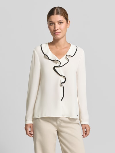 Frauenmodel trägt Regular Fit Bluse mit Volants von Marc Cain in Creme mit schwarzer Umrandung, V-Ausschnitt, Label-Detail, Ganzkörperansicht von vorne.