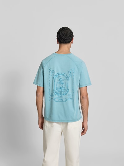 Männermodel trägt Regular Fit T-Shirt mit Logo-Print von MAISON KITSUNÉ aus reiner Bio-Baumwolle in Blau, Kurzärmelig, Rückenlänge 70 cm, Ganzkörperansicht Rückansicht.