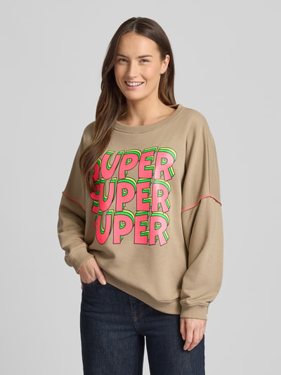 Frauenmodel trägt Oversized Sweatshirt mit gerippten Abschlüssen von miss goodlife aus Baumwolle, beige mit buntem Statement-Print, Nahaufnahme Oberkörper.