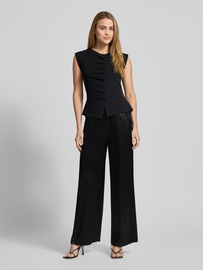 Vrouwenmodel draagt zwarte stoffen broek van zuivere viscose, los model, elastische band, steekzakken, Model 'Mucia' van Opus, volledige lichaamsvoorzijde.