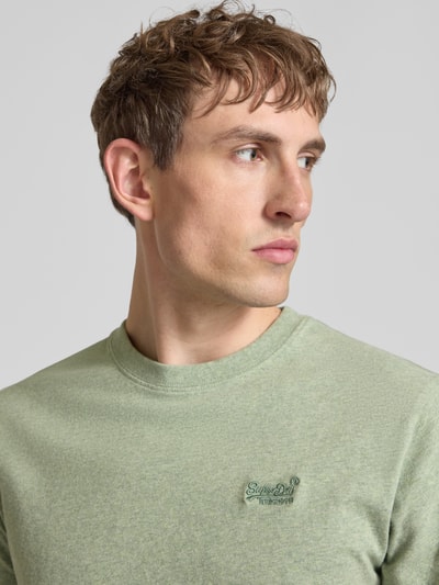 Männermodel trägt Regular Fit T-Shirt mit Logo-Stitching von Superdry aus Reine Baumwolle, Rundhalsausschnitt, Nahaufnahme Oberkörper.