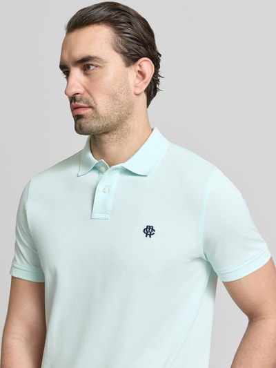 Männermodel trägt Slim Fit Poloshirt mit Logo-Stitching von MCNEAL in Hellblau, reine Baumwolle, Polokragen, Nahaufnahme Oberkörper.