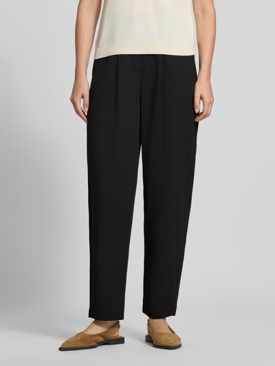 Frauenmodel trägt Relaxed Fit Anzughose mit Bundfalten Modell 'SC-SIHAM 103' von Soyaconcept in Schwarz, glatte Textur, Nahaufnahme Unterkörper, Damen Anzughose von Soyaconcept.