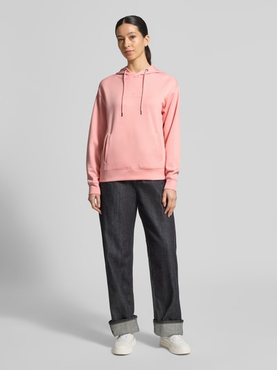 Modelka kobieca nosi różowy Hoodie mit Tunnelzug Modell 'IMA' od MSCH Copenhagen, prosty krój, kieszenie, miękki materiał, widok całej sylwetki z przodu.