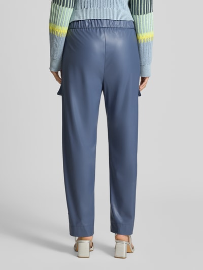 Frauenmodel trägt Straight Fit Hose in Leder-Optik mit Pattentaschen von Marc Cain in Blau, elastischer Bund, Ganzkörperansicht Rückansicht.