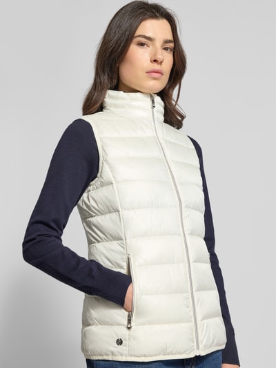 Frauenmodel trägt Steppweste mit Stehkragen von NAUTGÅRD, Regular-Fit, Reißverschluss, Reißverschlusstaschen, Nahaufnahme Oberkörper. Rückenlänge 64 cm, Schulterbreite 35 cm, Brustweite 46 cm bei Größe S.