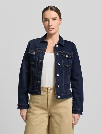 Frauenmodel trägt Slim Fit Jeansjacke aus Baumwoll-Mix von Tom Tailor in dunkelblauer Denim-Optik mit Umlegekragen, einreihiger Knopfleiste, Label-Prägung, Langarm mit Manschette, seitlichen Eingrifftaschen, Brusttaschen, Twill-Materialverarbeitung; Ganzkörperansicht von vorne.