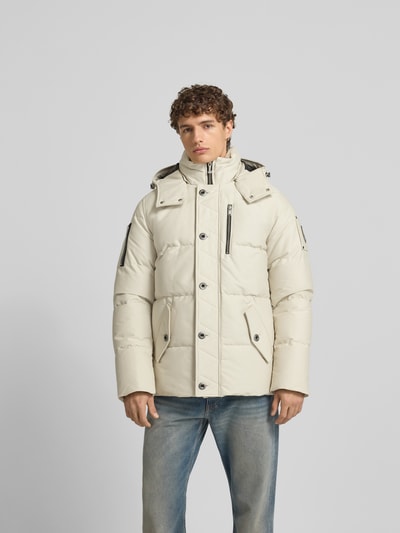 Männermodel trägt Daunenjacke mit Kapuze von Moose Knuckles in Beige, Baumwoll-Mix, Regular Fit, Pattentaschen, Ganzkörperansicht von vorne.