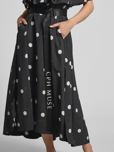 Frauenmodel trägt Midikleid mit Gürtel und Carmen-Ausschnitt Modell 'FIE' von Copenhagen Muse, schwarz mit weißen Punkten, Lyocell-Mix, taillierter Schnitt, Carmen-Ausschnitt mit Volant, Gürtel mit Doppel-D-Ring, Label-Print, Ganzkörperansicht von vorne.