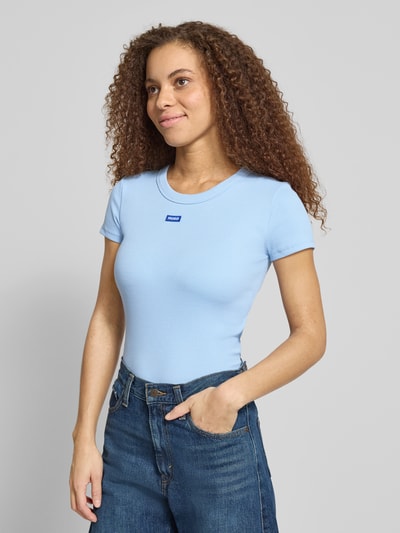 Frauenmodel trägt Slim Fit T-Shirt aus baumwoll-mix Modell 'EASY TEE' von HUGO BLUE, efekt: jednolity kolor, krój slim fit, naszywka z logo, wyhaftowane logo, okrągły dekolt, krótki rękaw, wykończenie materiału: prążkowanie, materiał: mieszanka bawełny, jasnoniebieski, gładka faktura, ganzkörperansicht z przodu