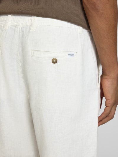 Männermodel trägt Loose Fit Hose aus Baumwoll-Leinen-Mix Modell 'BRODY' von SELECTED HOMME in Unifarbe mit Label Patch, Detailaufnahme Rückansicht.