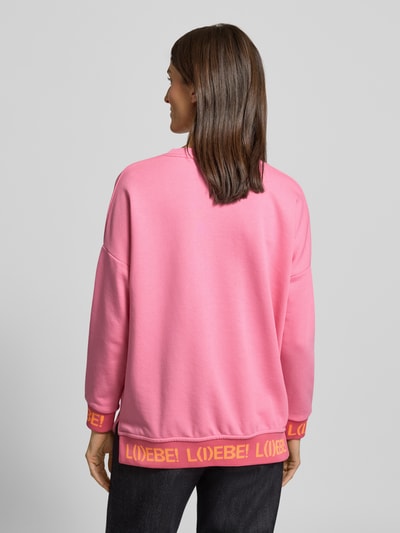 Frauenmodel trägt Oversized Sweatshirt mit Statement-Print von miss goodlife in Pink mit gerippten Abschlüssen, reine Baumwolle, Ganzkörperansicht Rückansicht.