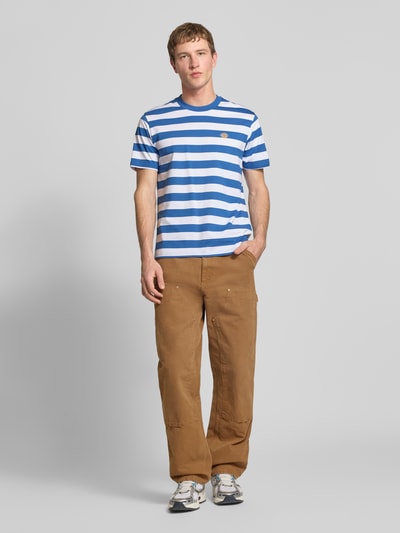 Männermodel trägt T-Shirt mit Label-Stitching Modell 'RIVERGROVE' von Dickies, blau-weiß gestreift, Rundhalsausschnitt, Baumwolle, Ganzkörperansicht von vorne.