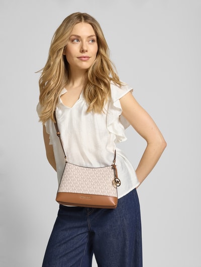 Modelka nosi torebkę z wzorem z logo model 'ANDIE' od MICHAEL Michael Kors, z główną przegrodą na zamek błyskawiczny, aplikacją z logo i paskiem na ramię, szerokość w rozmiarze 1: 20 cm, długość: 17 cm, głębokość: 8 cm, długość paska: 114 cm, jasne i brązowe kolory, faktura skóropodobna, zdjęcie całej sylwetki z przodu.