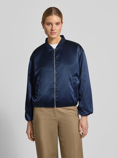 Kobiece model nosi Regular Fit Blouson mit College-Kragen od Tom Tailor, efekt: jednolity kolor, krój regular fit, kształt kołnierza: college, zapięcie: zamek błyskawiczny, rękawy: długi rękaw, zakończenie rękawów: elastyczne, wykończenie: elastyczne, wpuszczane kieszenie, wykończenie materiału: satyna; całe ciało widziane z przodu