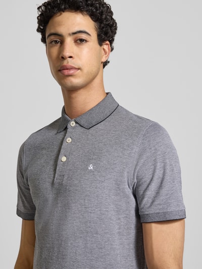 Männermodel trägt Slim Fit Poloshirt mit Viskose-Anteil Modell 'Paulos' von JACK & JONES, Baumwoll-Mix, Grau, Logo-Stitching, Nahaufnahme Oberkörper.