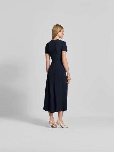Frauenmodel trägt Midikleid aus Viskose-Mix von Victoria Beckham in Dunkelblau mit Rundhalsausschnitt und taillierter Passform, Ganzkörperansicht Rückansicht.