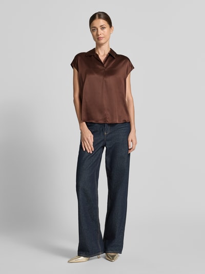 Frauenmodel trägt Regular Fit Hemdbluse aus reiner Seide von Luisa Cerano in Braun, glatte Oberfläche, kombiniert mit Jeans, Ganzkörperansicht von vorne. Rückenlänge bei Größe 36: 60 cm, Hemdblusenkragen, gelegte Falte, kurzärmeliges Design.