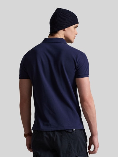 Männermodel trägt dunkelblaues Regular Fit Poloshirt aus reiner Baumwolle von Polo Ralph Lauren, kurzarm, Ganzkörperansicht Rückansicht.