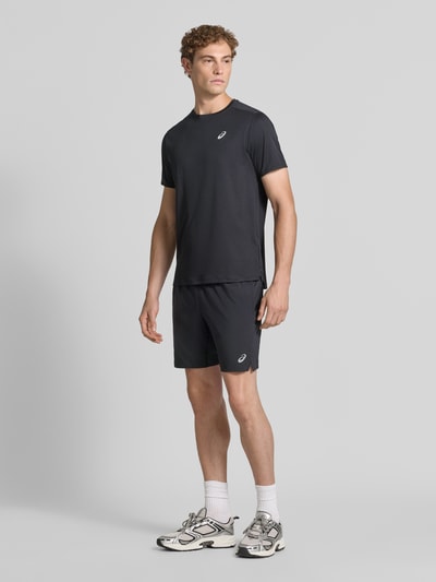 Männermodel trägt Regular Fit Shorts mit integriertem Slip Modell 'Core' von ASICS TIGER, Schwarz, mit Logo-Print, elastischer Bund, Ganzkörperansicht von vorne. Bundweite 38 cm, Innenbeinlänge 17 cm bei Größe M.