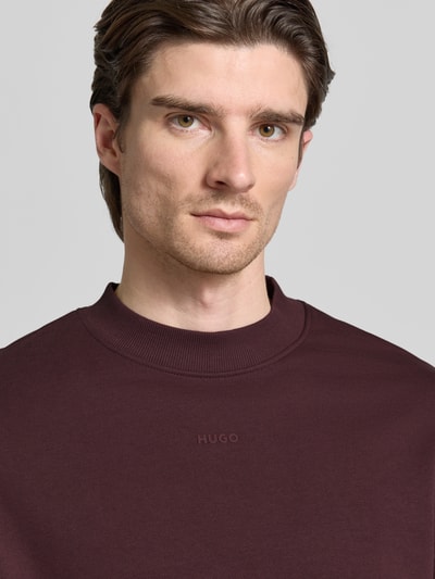 Männermodel trägt Regular Fit Sweatshirt aus reiner Baumwolle Modell 'DAPOCREW' von HUGO, Optik: Unifarben, Label-Print, Nahaufnahme Oberkörper.