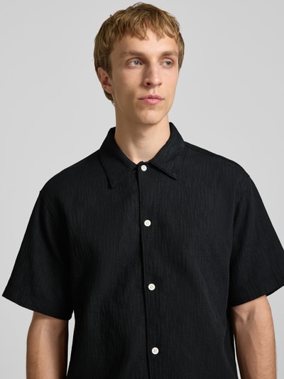 Männermodel trägt Regular Fit Freizeithemd mit Strukturmuster Modell 'MONTAUK' von Jack & Jones, zwarte katoen, knopen, kentkraag, Nahaufnahme Oberkörper.