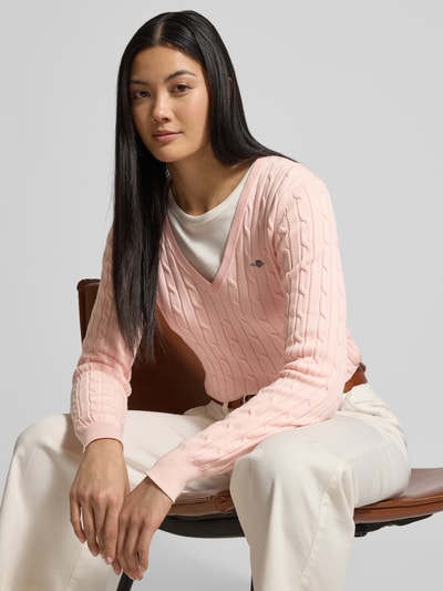 Kobiece model prezentuje Strickpullover mit Zopfmuster und Label-Stitching od Gant w kolorze jasnoróżowym, slim fit, przód, zbliżenie na górną część ciała.