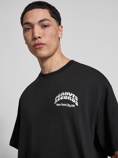 Männermodel trägt Regular Fit T-Shirt aus reiner Baumwolle Modell 'PEANUTS' von Only & Sons in Schwarz, Nahaufnahme Oberkörper.