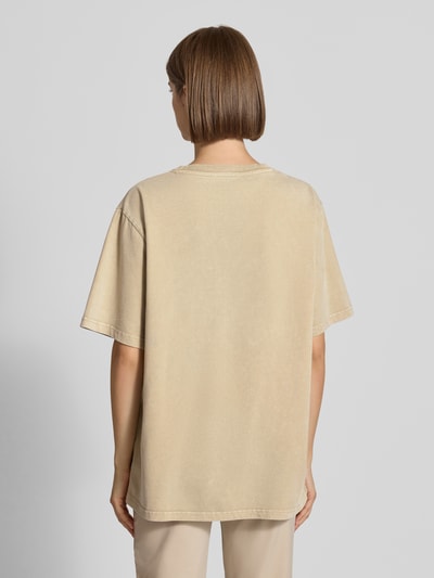 Frauenmodel trägt T-Shirt mit Rundhalsausschnitt Modell 'AM to PM' von OH APRIL in Beige, reine Baumwolle, oversized, Rückenlänge 68 cm, Ganzkörperansicht Rückansicht.