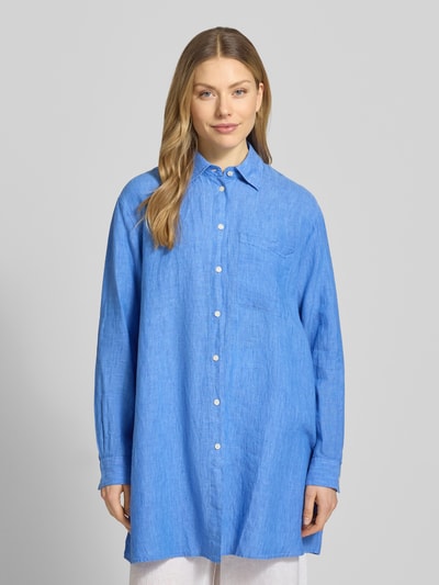 Frauenmodel trägt Relaxed Fit Longbluse aus Leinen Modell 'TAHIA' von 0039 Italy in Blau mit Hemdblusenkragen, Knopfleiste, Brusttasche, Rückenlänge 86 cm, Ärmellänge 58 cm, Ganzkörperansicht von vorne.