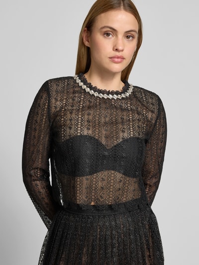 Frauenmodel trägt Slim Fit Longsleeve aus floraler Spitze von Self-Portrait aus reiner Baumwolle mit Ziersteinbesatz und Schulterpolstern, Nahaufnahme Oberkörper.