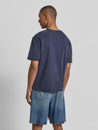 Männermodel trägt T-Shirt mit Motiv-Print und Rundhalsausschnitt von Guess, reine Baumwolle, Regular-Fit, Rückenlänge 68 cm, Ganzkörperansicht Rückansicht.