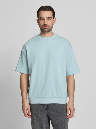 Männermodel trägt Oversized T-Shirt mit Rundhalsausschnitt von Lindbergh in Hellblau, Baumwoll-Mix, Label-Detail, Ganzkörperansicht von vorne. Rückenlänge bei Größe M: 70 cm.