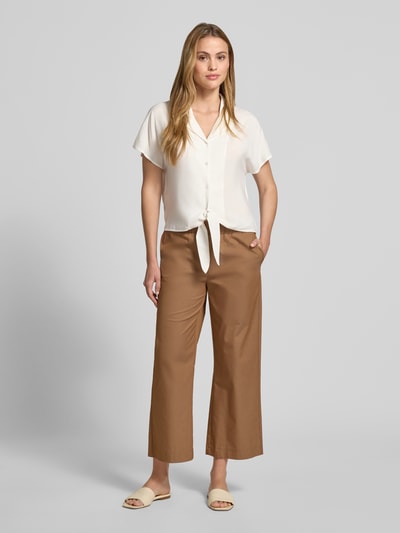 Frauenmodel trägt Regular Fit Bluse aus Viskose mit Knotendetail Modell 'RADIA' von Soyaconcept in Creme, Reverskragen, Knopfleiste, glatte Textur, Rückenlänge bei Größe S 55 cm, Ärmellänge 10 cm, Ganzkörperansicht von vorne.