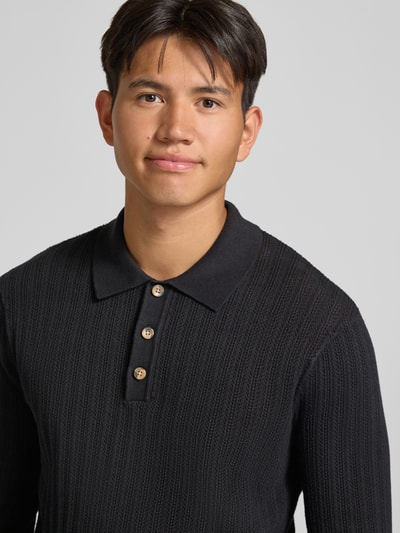 Männermodel trägt Regular Fit Poloshirt aus Baumwoll-Mix Modell 'MOON' von ONLY & SONS in Schwarz, Nahaufnahme Oberkörper.