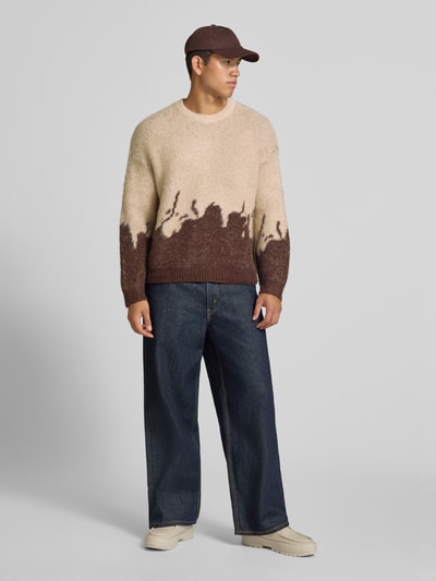 Männermodel trägt Strickpullover mit gerippten Abschlüssen von ANOTHER COTTON LAB in Beige-Braun, weiter Schnitt, elastischer Material-Mix, Ganzkörperansicht von vorne.