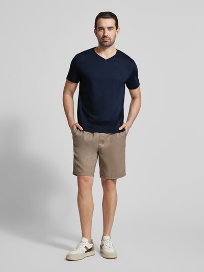 Männermodel trägt Regular Fit T-Shirt aus reiner Baumwolle von Tom Tailor in Dunkelblau, unifarben, mit Logo-Stitching, V-Ausschnitt, Kurzarm, Jersey-Textur, Ganzkörperansicht von vorne.