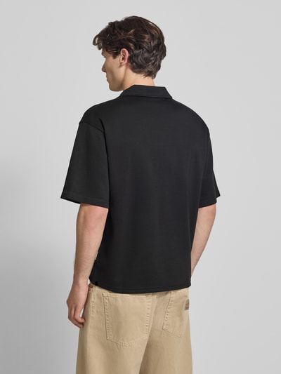 Männermodel trägt Regular Fit Poloshirt mit Logo Modell 'Eddie' von Redefined Rebel in Schwarz aus Baumwoll-Mix, Rückenlänge 73 cm, Ganzkörperansicht Rückansicht.