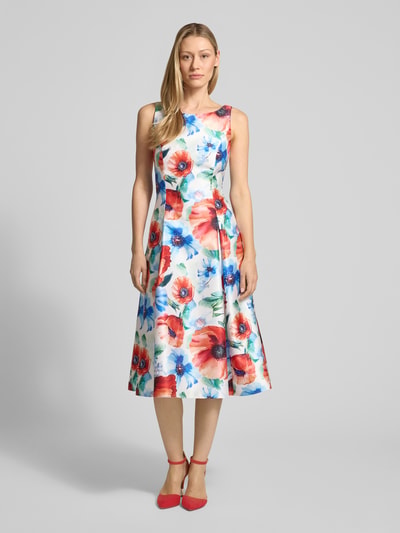 Frauenmodel trägt Knielanges Cocktailkleid im Allover-Look von Vera Mont, A-Linie, bunte Blumenfarben, Rundhalsausschnitt, Ganzkörperansicht von vorne.