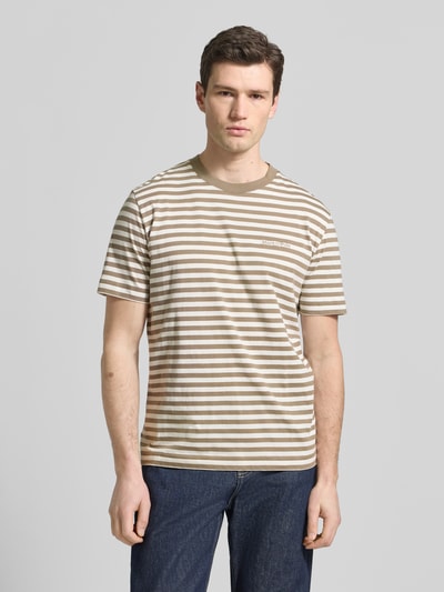 Männermodel trägt Regular Fit T-Shirt aus reiner Baumwolle von Marc O'Polo mit braun-beigen Streifen und Label Stitching, Ganzkörperansicht von vorne.