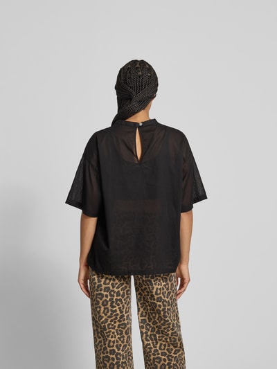 Frauenmodel trägt T-Shirt in semitransparenter Optik von black palms aus reiner Baumwolle, lockerer Schnitt, Rückenlänge 66 cm, Ganzkörperansicht Rückansicht.