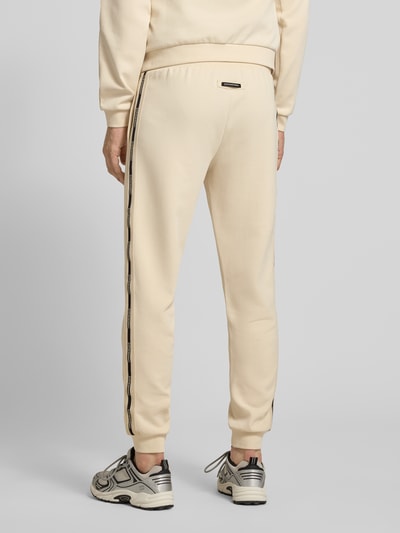 Männermodel trägt Sweatpants aus Baumwoll-Mix von EA7 Emporio Armani in Beige mit elastischem Bund, Eingrifftaschen, lockerer Passform, Ganzkörperansicht Rückansicht.
