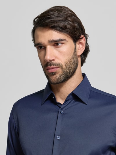 Männermodel trägt Regular Fit Businesshemd aus Stretch-Twill Modell 'P-JOE-KENT-C1-222' von BOSS in dunkelblau, Nahaufnahme Oberkörper.
