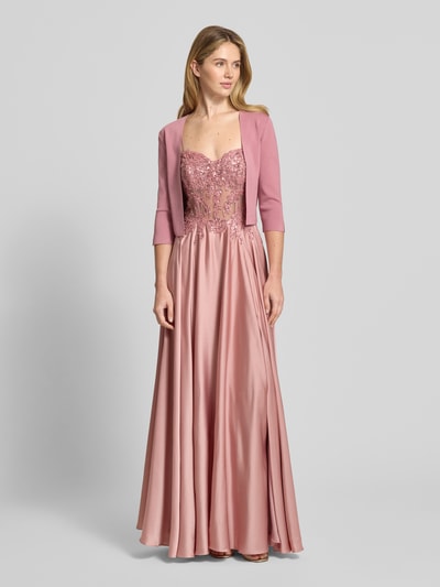 Frauenmodel trägt Bolero mit 3/4-Arm von Vera Mont aus Viskose-Mix mit Stretch-Anteil in zartem Rosa, körpernahe Passform, offene Vorderseite, kombiniert mit bodenlangem Kleid, Ganzkörperansicht von vorne.