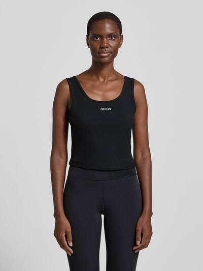 Frauenmodel trägt schwarzes Slim Fit Top mit Logo-Stitching Modell 'Circe' von Guess, elastischer Material-Mix, Ganzkörperansicht von vorne.