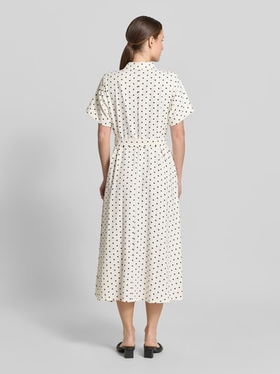 Frauenmodel trägt Hemdblusenkleid mit Bindegürtel Modell 'BlakeLL' von LOLLYS LAUNDRY, cremefarben mit schwarzen Punkten, Taillierter Schnitt, Midikleid, Hemdblusenkragen, Knopfleiste, Ärmel mit Aufschlag, Rückenlänge bei Größe S 122 cm, Brustweite 50 cm, Ärmellänge 21 cm, Ganzkörperansicht Rückansicht.