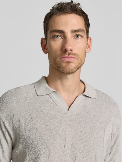 Männermodel trägt Relaxed Fit Poloshirt aus reiner Baumwolle Modell 'ASURFO' von BOSS Orange in Optik: Unifarben, Struktur, Label-Applikation, Polokragen, V-Ausschnitt, Kurzarm, Materialverarbeitung: Frottee, Nahaufnahme Oberkörper.