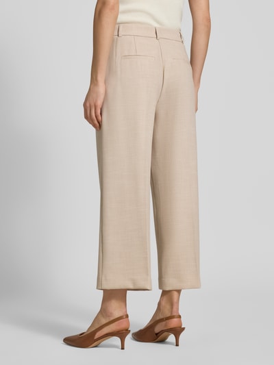 Frauenmodel trägt Relaxed Fit Stoffhose mit Viskose-Anteil und Bügelfalten von Comma in Beige, Elastischer-Material-Mix, Ganzkörperansicht Rückansicht. Bundweite 39 cm, Innenbeinlänge 63 cm, Gürtelschlaufen, Eingriffstaschen, Gesäßtaschen.